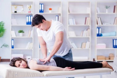 Genç doktor kayropraktik uzmanı kadın hastaya masaj yapıyor.