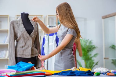 Atölyede çalışan genç bayan terzi yeni elbise üzerinde çalışıyor.