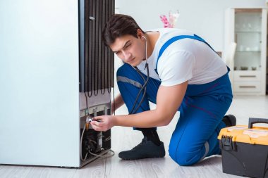 Tamirci müteahhit DIY konseptinde buzdolabını tamir ediyor.