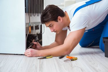 Tamirci müteahhit DIY konseptinde buzdolabını tamir ediyor.