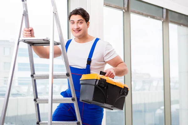 Jovem reparador subindo escada no local de construção — Fotografia de Stock