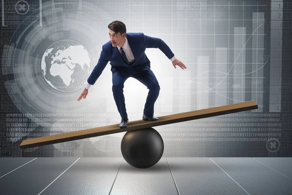 Businessman trying to balance on ball and seesaw — Stock Photo, Image