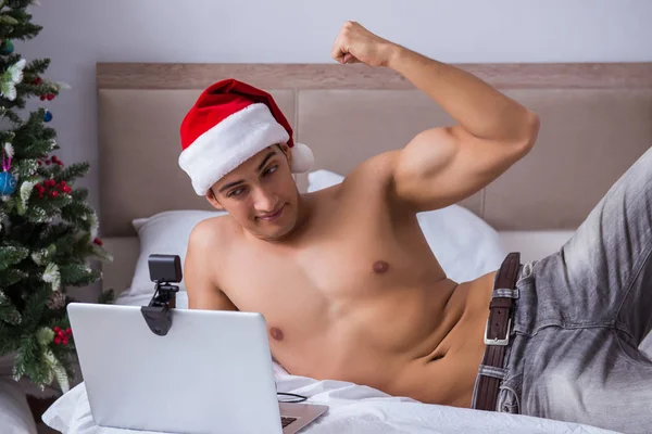 Sexy mężczyzna w łóżko nosić Santa kapelusz w Boże Narodzenie koncepcja — Zdjęcie stockowe