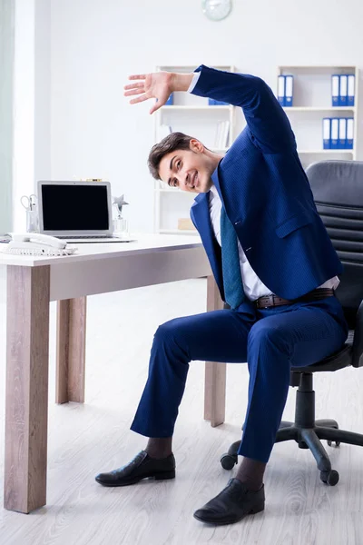 Joven empresario haciendo deporte estiramiento en el lugar de trabajo —  Fotos de Stock