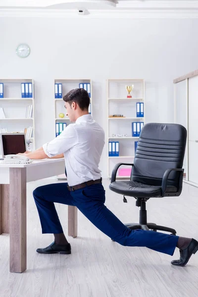Young businessman doing sports stretching at workplace — Stock Photo, Image