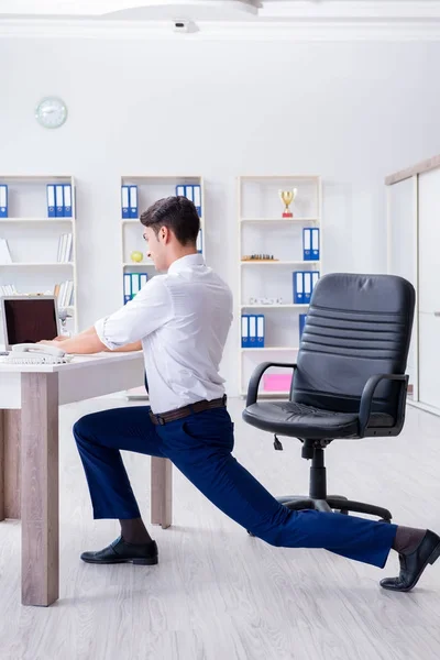 Joven empresario haciendo deporte estiramiento en el lugar de trabajo —  Fotos de Stock