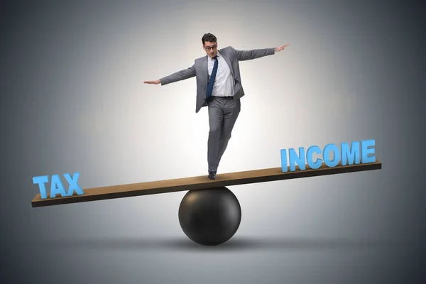 Businessman balancing between income and tax in business concept — Stock Photo, Image