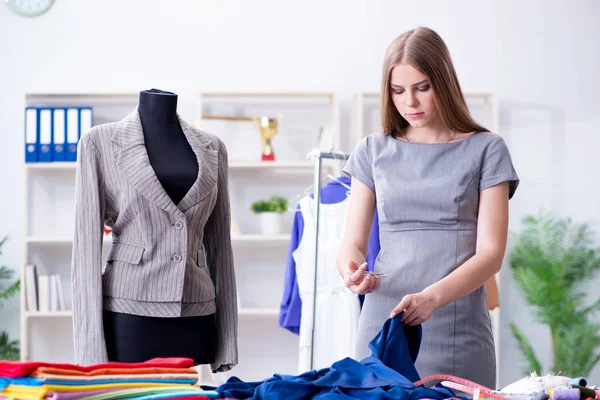 Mujer joven sastre trabajando en taller sobre vestido nuevo — Foto de Stock