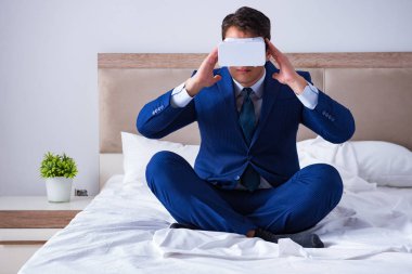 Yatak odasında sanal gerçeklik kulaklığı takan bir iş adamı.