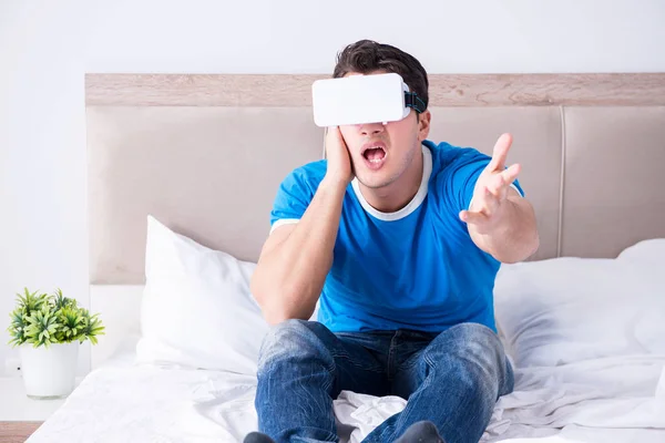 Jovem na cama vestindo um vr realidade virtual head set — Fotografia de Stock