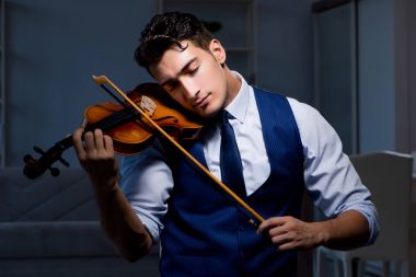 Genç müzisyen evde keman çalıyor.