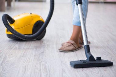 Kadın elektrikli süpürgeyle temizlik yapıyor.