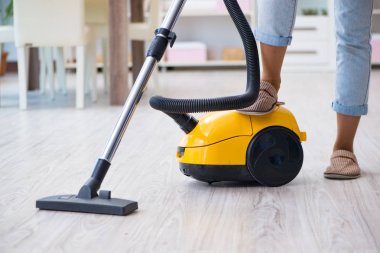 Kadın elektrikli süpürgeyle temizlik yapıyor.