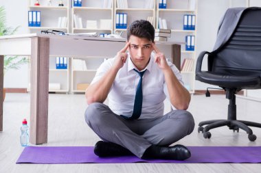 Adam stresle baş etmek için ofiste meditasyon yapıyor.