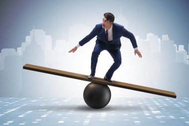 Top ve tahterevalli üzerinde denge kurmaya çalışan bir işadamı