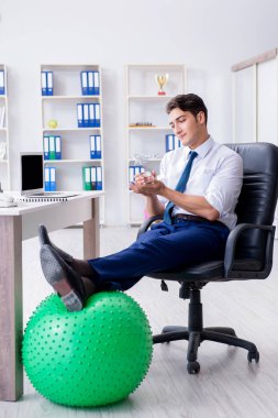 Genç işadamı iş yerinde spor yapıyor.