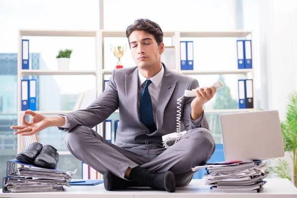 Businessman sitting on top of desk in office — Stock Photo, Image