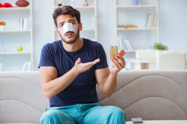 Genç adam estetik cerrahi burnundan sonra evde iyileşiyor.