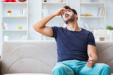 Genç adam estetik cerrahi burnundan sonra evde iyileşiyor.