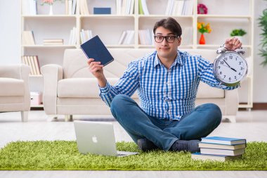 Genç yakışıklı adam evde yerde oturuyor.