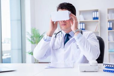 Sanal gerçeklik kulaklığı olan genç doktor ofiste çalışıyor.