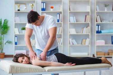 Genç doktor kayropraktik uzmanı kadın hastaya masaj yapıyor.