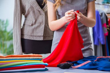 Atölyede çalışan genç bayan terzi yeni elbise üzerinde çalışıyor.