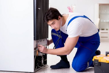 Tamirci müteahhit DIY konseptinde buzdolabını tamir ediyor.
