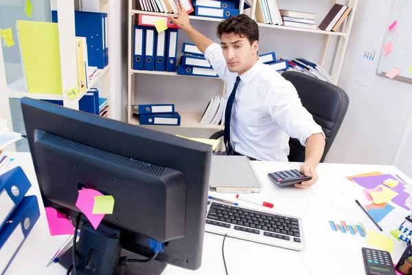 Geschäftsmann arbeitet im Büro mit Stapeln von Büchern und Papieren — Stockfoto