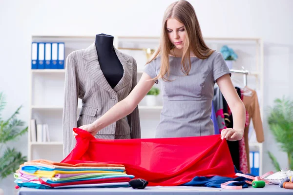 Mujer joven sastre trabajando en taller sobre vestido nuevo — Foto de Stock