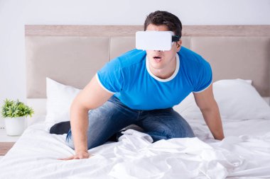 Yatakta sanal gerçeklik başlığı takan genç bir adam.
