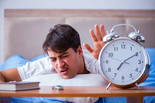 Hombre en la cama frustrado sufriendo de insomnio con un zueco de alarma — Foto de Stock