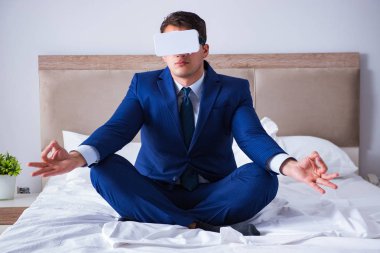 Yatak odasında sanal gerçeklik kulaklığı takan bir iş adamı.
