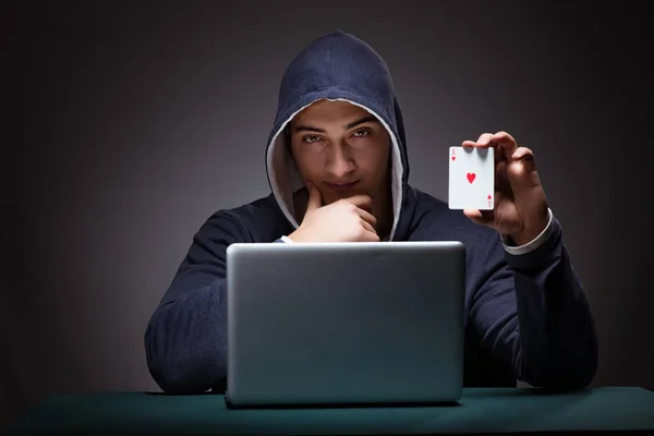 Jovem usando um capuz sentado na frente de um computador portátil — Fotografia de Stock