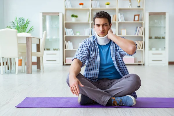 Boynu yaralanmış bir adam evde yerde meditasyon yapıyor. — Stok fotoğraf