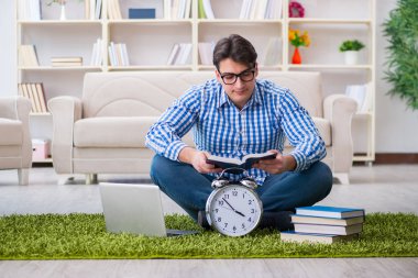 Genç yakışıklı adam evde yerde oturuyor.