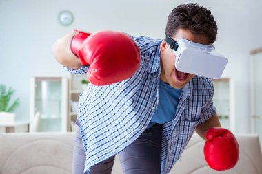 Sanal gerçeklik gözlüğü takan adam boks oyunu oynuyor.