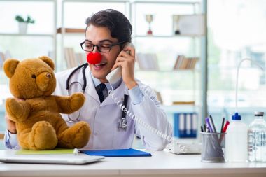 Hastane kliniğinde oyuncak taşıyan komik bir çocuk doktoru.