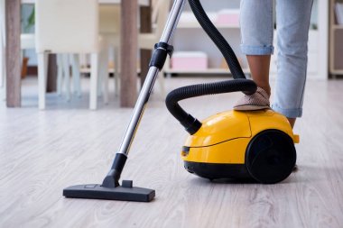 Kadın elektrikli süpürgeyle temizlik yapıyor.