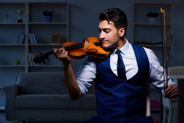 Genç müzisyen evde keman çalıyor.