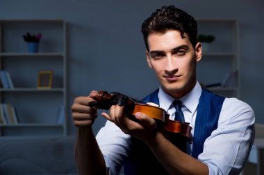 Genç müzisyen evde keman çalıyor.