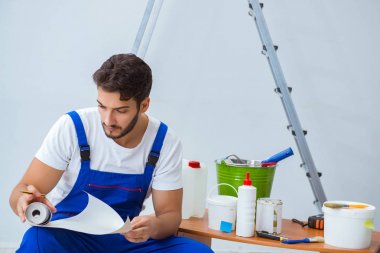 Tamirci, duvar kağıdıyla evde tadilat yapıyor.