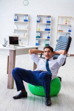 Genç işadamı iş yerinde spor yapıyor.