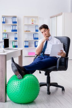 Genç işadamı iş yerinde spor yapıyor.