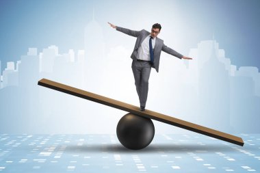 Top ve tahterevalli üzerinde denge kurmaya çalışan bir işadamı
