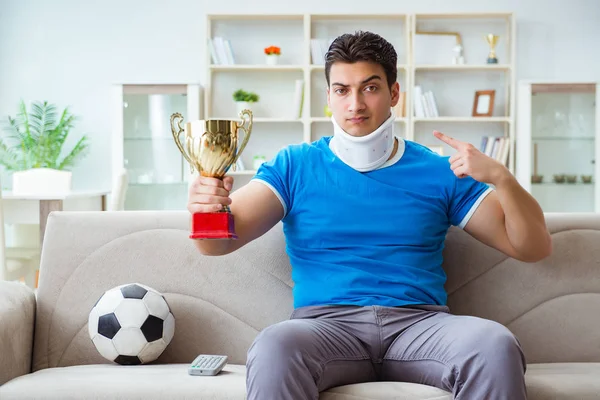Uomo con infortunio al collo guardando calcio a casa — Foto Stock