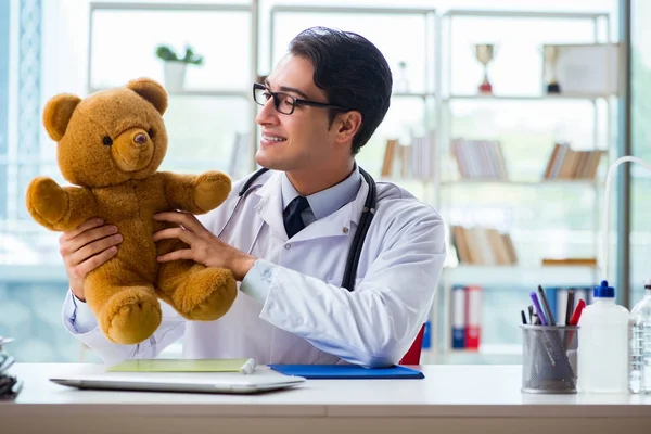 Barnläkare med leksak sittande på kontoret — Stockfoto