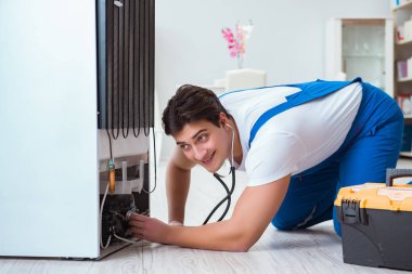 Tamirci müteahhit DIY konseptinde buzdolabını tamir ediyor.