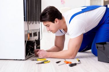 Tamirci müteahhit DIY konseptinde buzdolabını tamir ediyor.