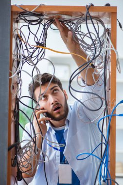 Elektrik teknisyeni tamir konseptinde kabloları çözmeye çalışıyor.